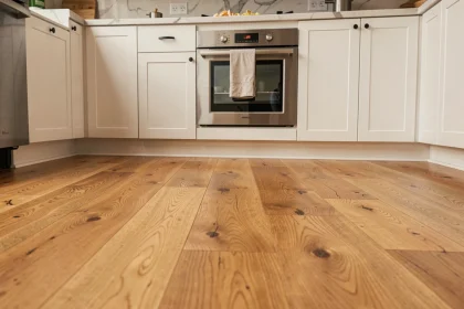 Parquet en chêne naturel dans une cuisine moderne avec armoires blanches et plan de travail en marbre